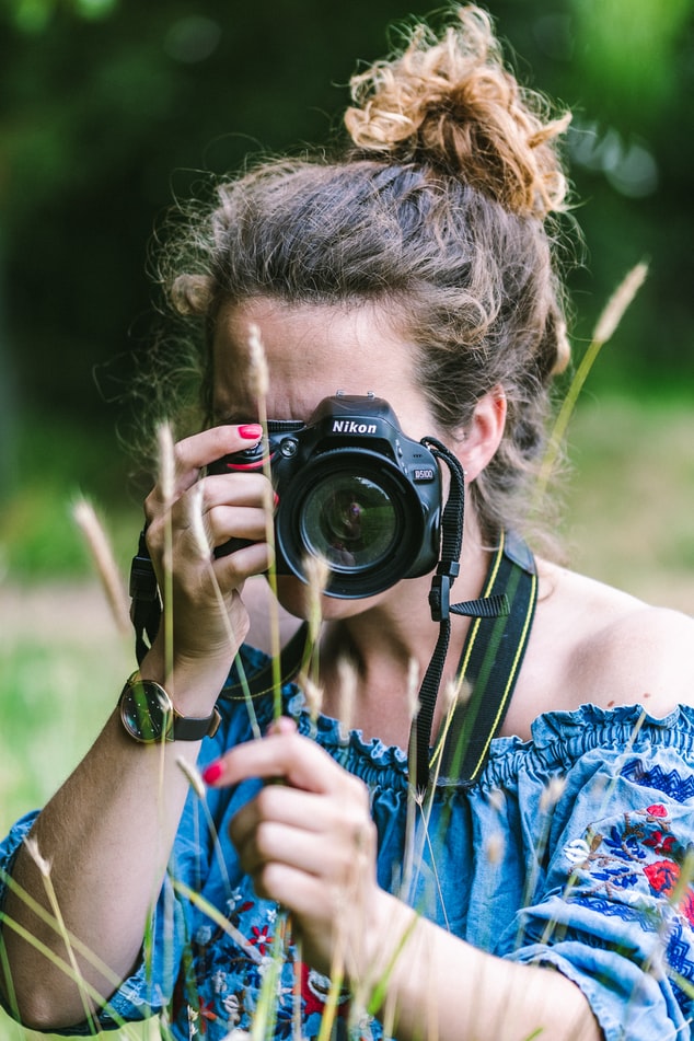 Travel photographer taking a photo behind grass