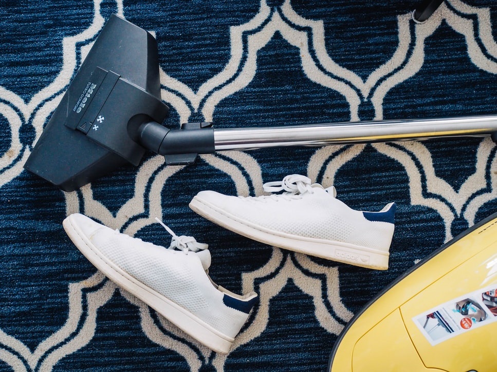 Shoes on clean carpet next to a vacuum