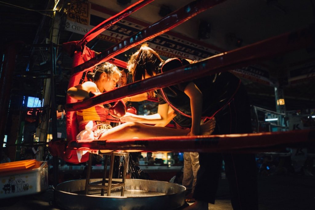 MMA fighter sitting in the corner of a ring with trainers