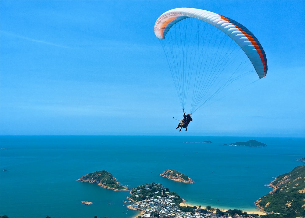 Two people parachuting in the sky above oceanside cliffs