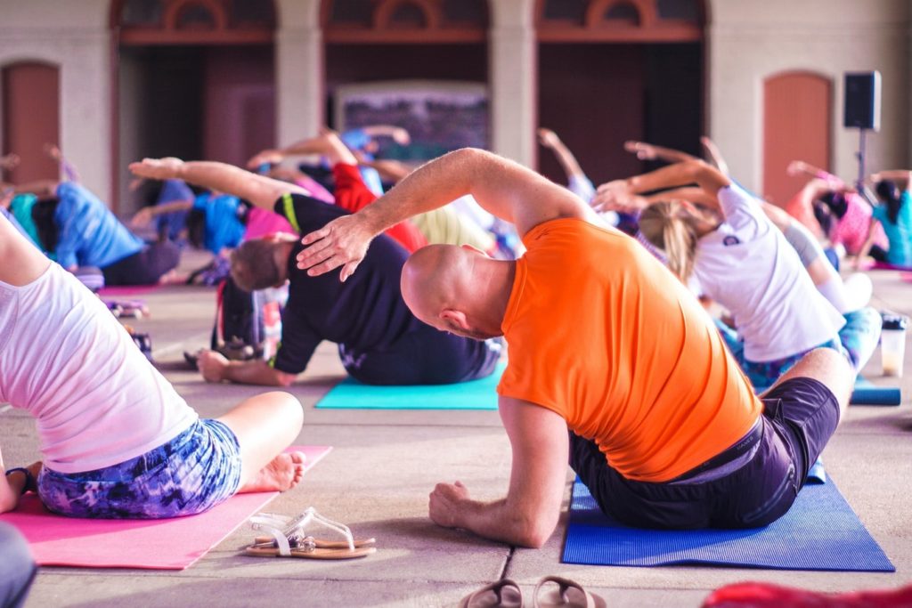 Large yoga class following the yoga instructor in a pose