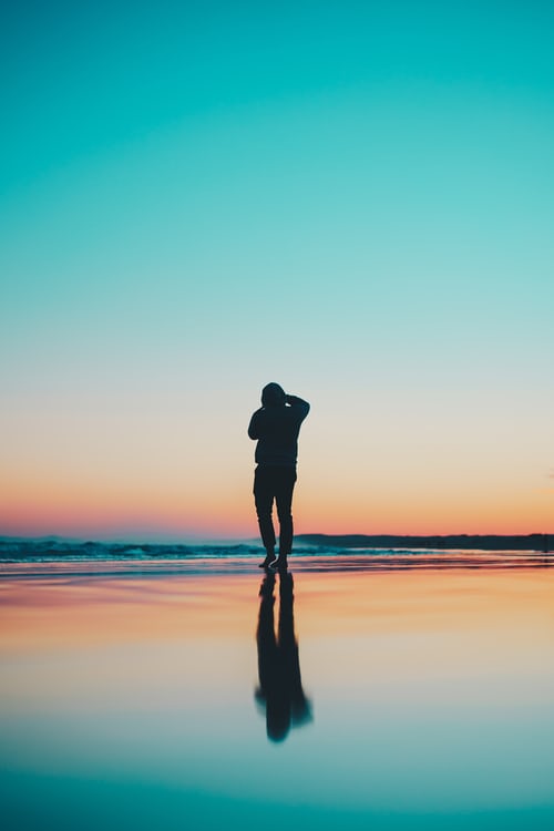 Silhouette and reflection of a landscape photographer taking pictures of the ocean